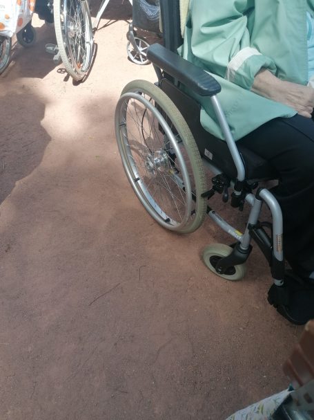 Nahaufnahme eines Rollstuhls mit einer Person, die auf der rechten Seite sitzt.