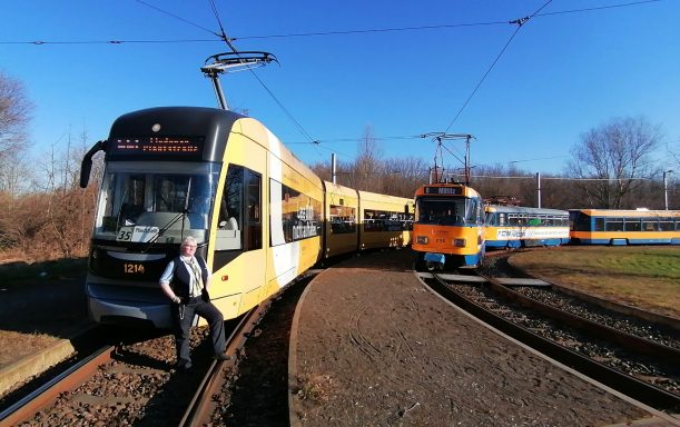 Zwei Trams stehen auf einem Gleis in einer hellen, sonnigen Umgebung.