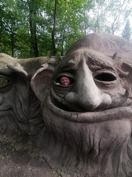 Gemeinsam Spaß haben Lächelnde, große Steinfigur eines Trolls aus einer Parklandschaft.